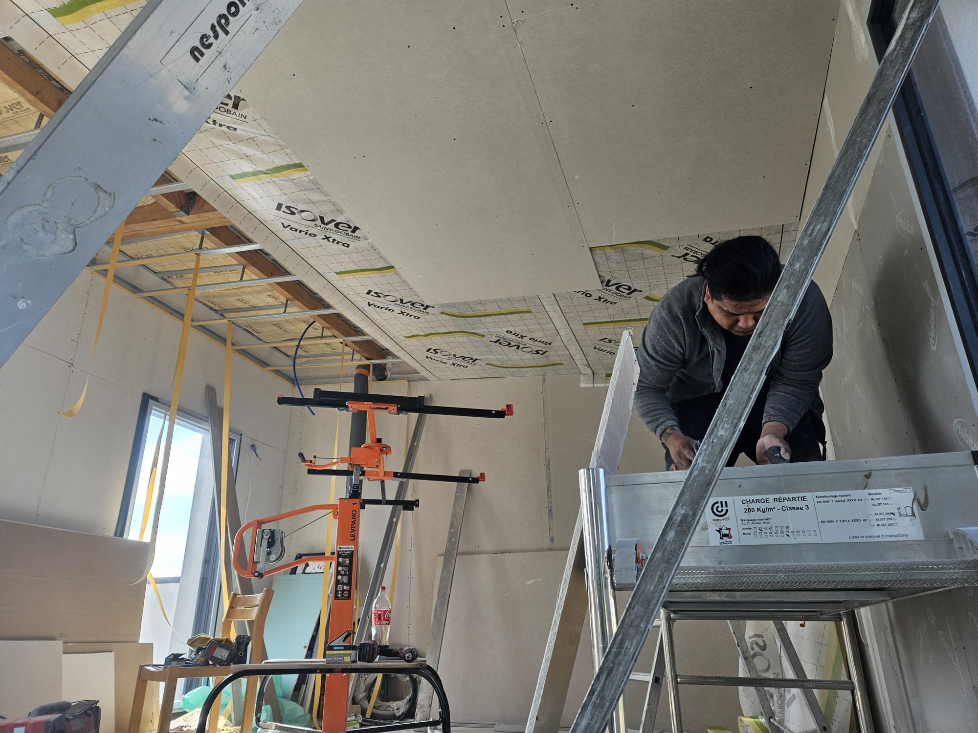 Artisan réalisant la pose d’un plafond en plaques de plâtre lors de travaux de rénovation intérieure